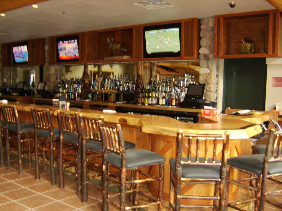 The live-edge pine bar with hickory-log stools, a deep back bar and televisions overhead